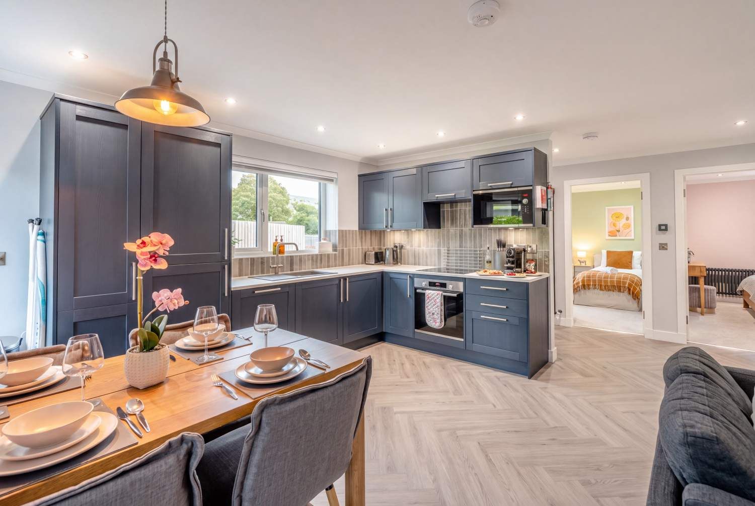 Open-plan kitchen and dining area with navy units and a set oak table in a self-catering holiday cottage near Dunfermline, Fife